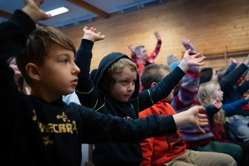 Ivrige elever rekker opp hendene i gymsalen