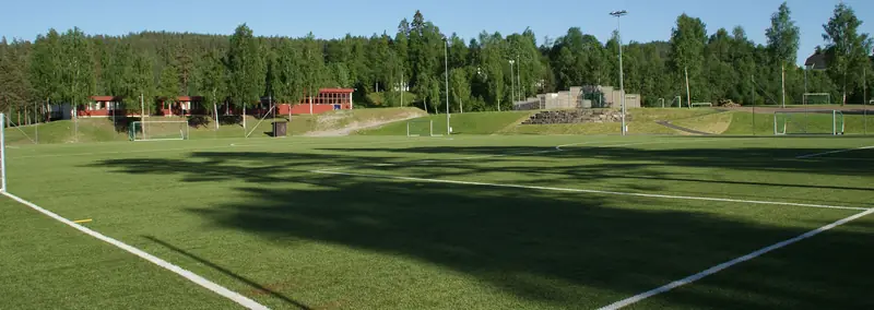 Fotballbanen ved skolen en sommerdag, med skog rundt
