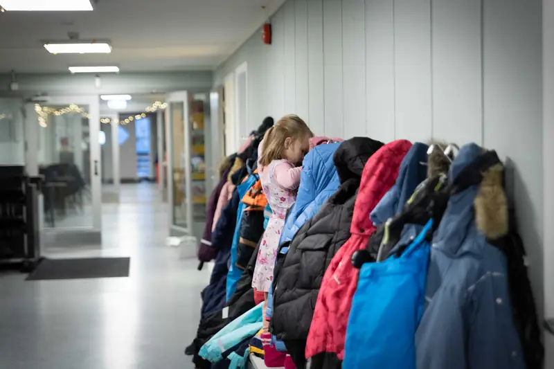 Fargerike vinterjakker henger på knagger i skolens gang