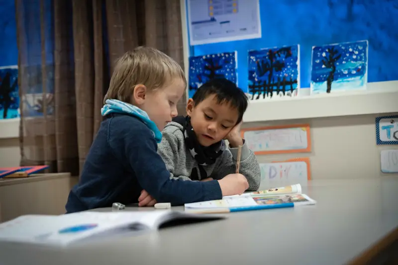 To gutter leser sammen ved et bord i klasserommet