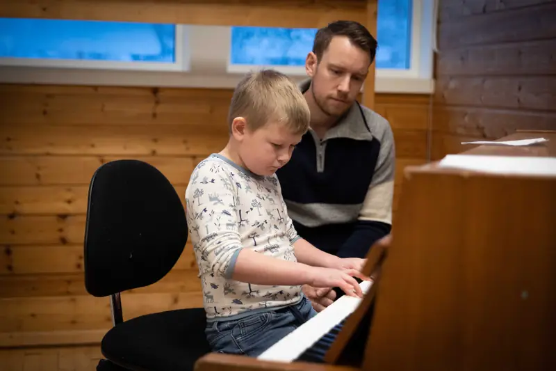 Lærer og elev spiller piano sammen